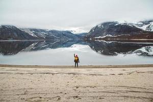 man standing on background of mountains and lake makes a photo