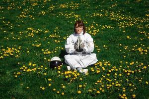 Mujer astronauta sin casco se sienta en un césped verde entre flores foto