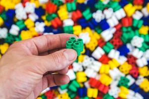 Hand with colorful plastic bricks on a colorful background photo