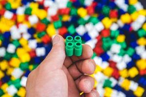 Hand with colorful plastic bricks on a colorful background photo