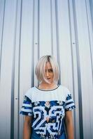 woman with short white hair stands on the background of metal wall photo