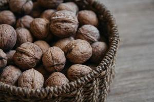 Walnuts in a round wicker basket on a wooden background photo