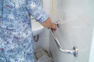 Mujer mayor asiática paciente uso inodoro baño manejar seguridad foto