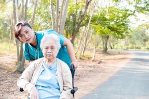Ayude y cuide a la mujer mayor asiática use el andador en el parque. foto