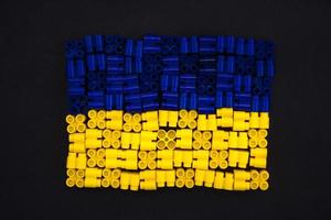 plastic bricks which form the Ukraine flag on black paper background photo