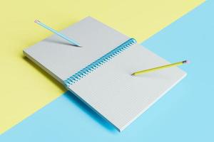 cuaderno abierto a cuadros con lápices flotando