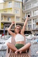 Woman sitting on the sun lounger listening to the music and dancing photo