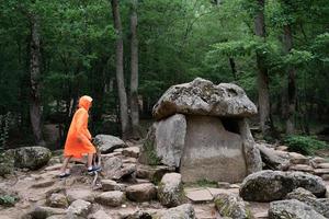 Mujer feliz en impermeable naranja caminando en el bosque foto