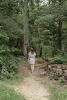 Back view of a woman walk along the forest in the early misty morning photo