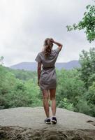 Young woman  standing on a big rock in the forest looking away photo