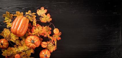 Autumn decorations with pumpkins and leaves top view on black photo