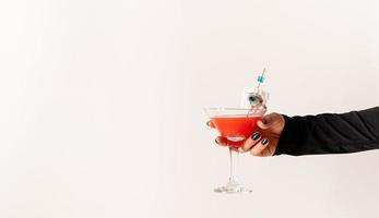 Woman hand with black nails holding glass with scary red halloween photo