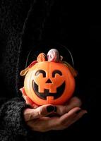 Creepy woman Halloween hand with black nails holding pumpkin