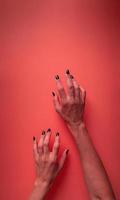 Mujer espeluznante manos de halloween con uñas negras sobre fondo rojo con sangre foto
