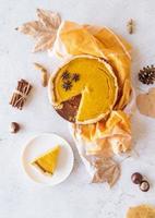 Homemade pumpkin pie with autumn leaves on rustic background, top view photo