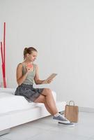 Young woman shopping online sitting at home on the bed