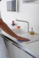 Man hand with rag cleaning the kitchen surfaces photo