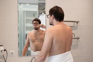 A young man brushing his teeth in the bathroom photo