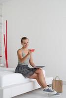 Young woman shopping online sitting at home on the bed