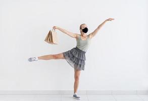 Mujer joven bailando ballet con bolsas de la compra en una máscara protectora foto