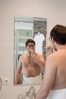 hombre joven cepillándose los dientes en el baño foto