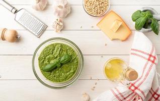 Fresh pesto in bowl with ingredients, top view flat lay on white