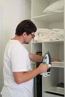 Young man ironing at home photo