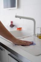 Man hand with rag cleaning the kitchen surfaces photo