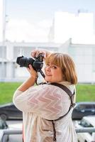 Retrato de mujer con sobrepeso tomando fotografías con una cámara en el exterior