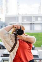 Retrato de mujer con sobrepeso tomando fotografías con una cámara en el exterior foto