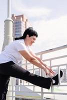 Smiling senior woman doing stretching outdoors on urban background photo