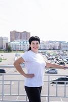 Smiling senior woman working out outdoors on urban background photo