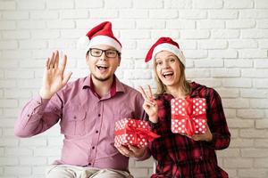 Happy christmas couple in santa hats on white brick wall background photo