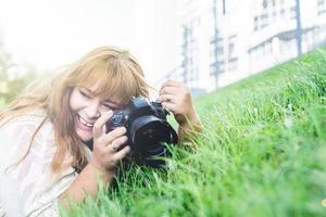 Retrato de mujer con sobrepeso tomando fotografías con una cámara en el parque foto