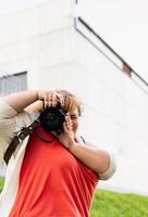 Retrato de mujer con sobrepeso tomando fotografías con una cámara en el parque foto