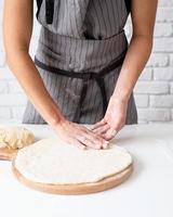 Mujer amasando masa en casa preparando pizza foto