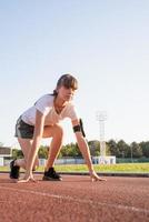 Young woman ready to race at stadium track photo
