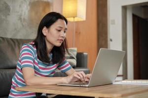 mujer asiática que usa la computadora portátil para el trabajo desde casa y el aprendizaje en línea.