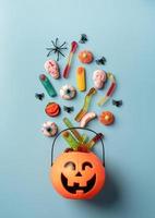 Various Halloween sweets and candies in a pumpkin pot, top view photo