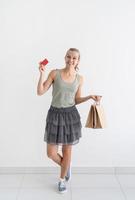 Mujer sonriente sosteniendo bolsas de compras ecológicas y tarjeta de crédito