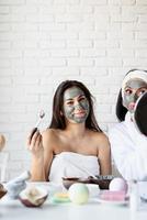 Beautiful woman applying facial mask doing spa procedures photo