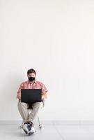 Hombre con máscara protectora estudiando en línea manteniendo la distancia social