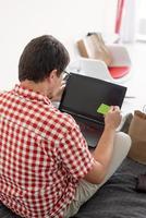 Back view of man shopping on internet with laptop looking photo