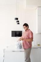 Man holding a disposable plastic bag with food delivery at the kitchen photo