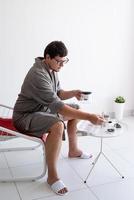 Man sitting in bathrobe making tea at home photo