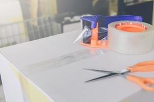 Preparing parcel for shipping with scissors and scotch tape cutter. photo