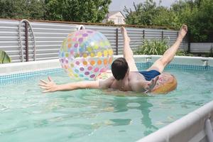 Young man having fun at the swimming pool on inflatable swim tube photo