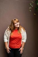 Overweight woman posing on the brown solid wall on the street photo