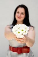 Young woman holding a bouquet of flowers on a gray solid background photo