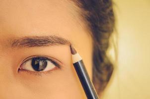 rostro de belleza de mujer asiática aplicando lápiz de cejas sobre la piel. foto